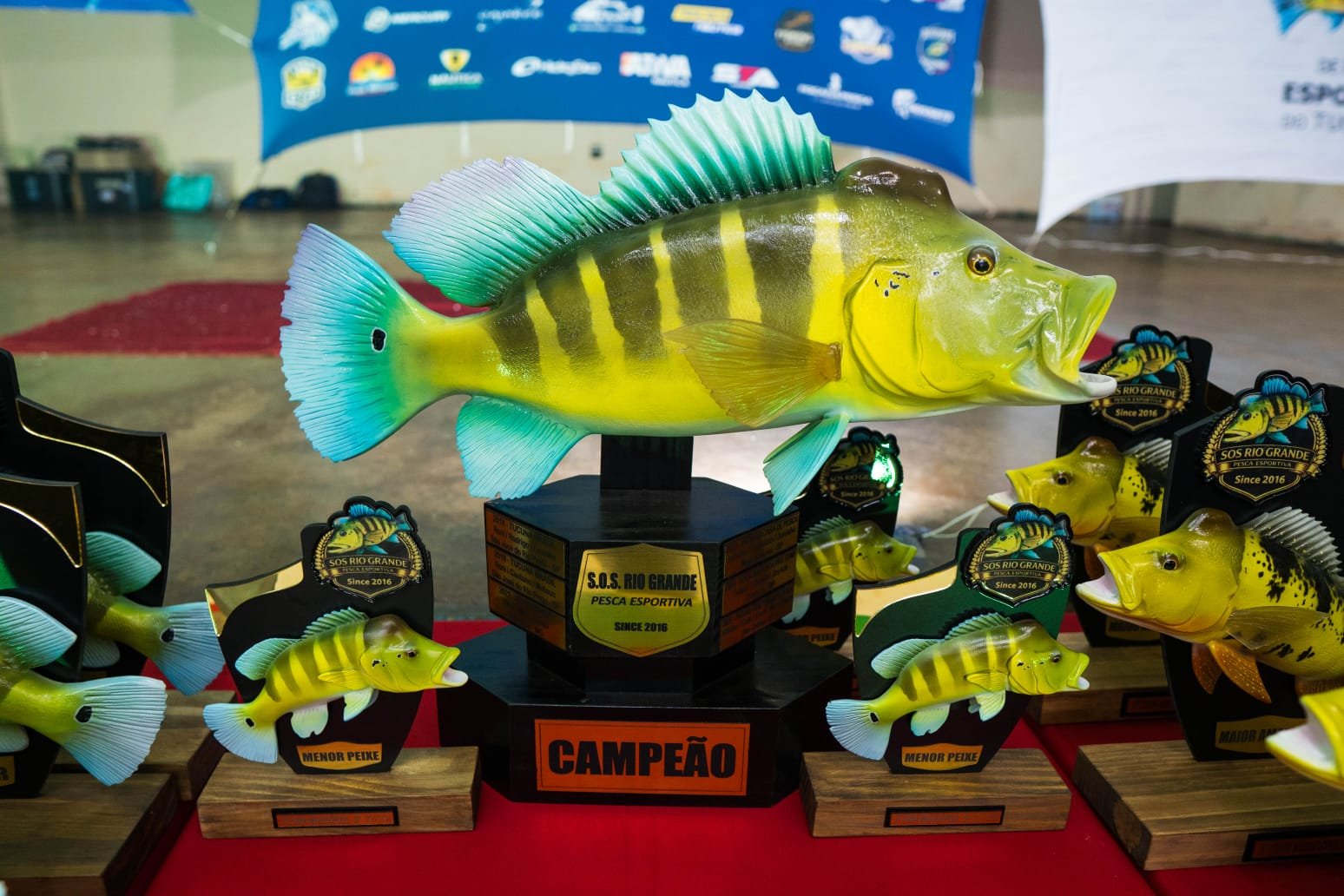 Troféus em forma de tucunaré exibidos em evento do S.O.S. Rio Grande
